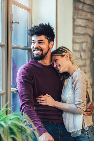 Genç bir çift pencere yanında, tuğla duvar arka plan sarılma portresi.