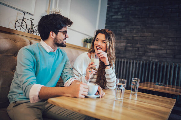  Beautiful loving couple sitting in a cafe drinking coffee and conversating. Love and romance concept.