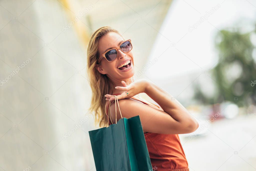 Beautiful woman holding shopping bags and smiling - outdoors