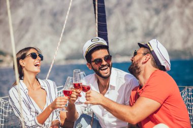 Yelkenli güvertesinde oturup eğlenen arkadaşlar. Tatil, seyahat, deniz, arkadaşlık ve insanlar kavramı.