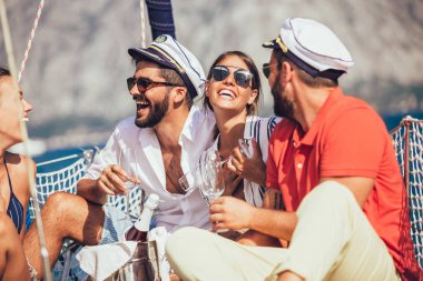 Yelkenli güvertesinde oturup eğlenen arkadaşlar. Tatil, seyahat, deniz, arkadaşlık ve insanlar kavramı.