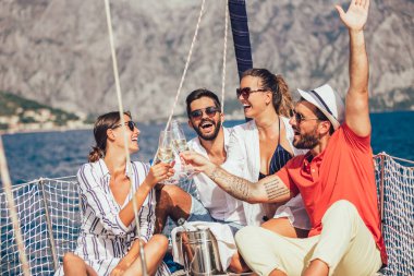 Yelkenli güvertesinde oturup eğlenen arkadaşlar. Tatil, seyahat, deniz, arkadaşlık ve insanlar kavramı.
