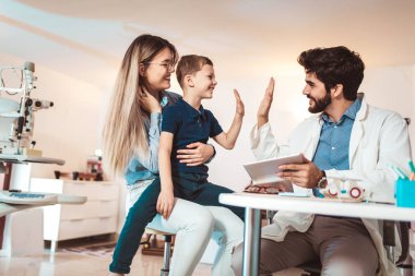 Anne ve oğlu optik dükkanında gözlük seçiyor..