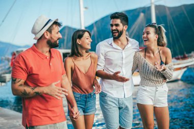 Bir turistik deniz tatil tekne ile liman tarafından arka planda yürüyen arkadaşlar