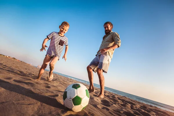快乐的父亲和儿子踢足球或足球在海滩有很好的家庭时间在夏天假日 — 图库照片