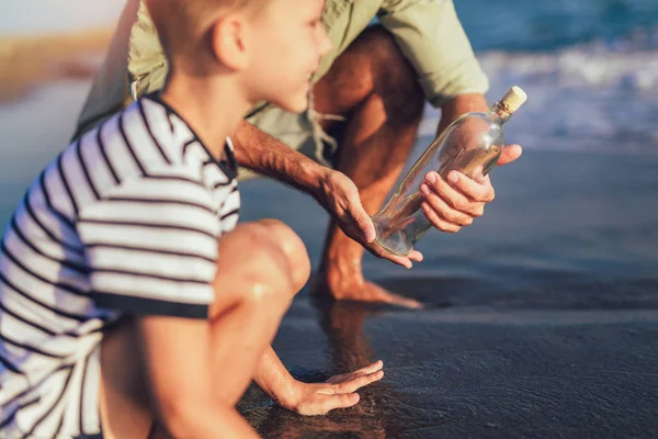 父亲和儿子在海滩与消息在瓶子里 — 图库照片