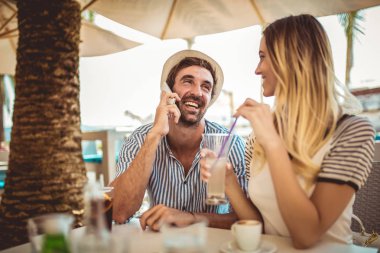 Mutlu çift açık havada telefon kullanarak kafede oturan