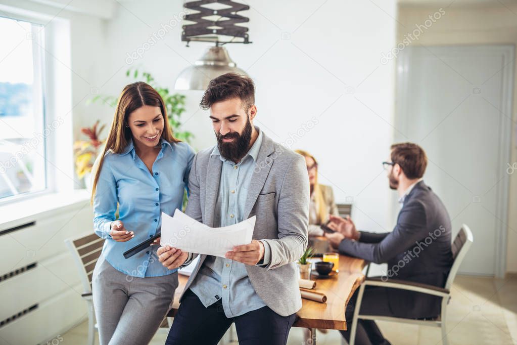 Portrait of two young businesspeople while colleague in background
