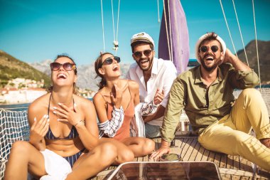 Yelkenli güvertesinde oturup eğlenen arkadaşlar. Tatil, seyahat, deniz, arkadaşlık ve insanlar kavramı.