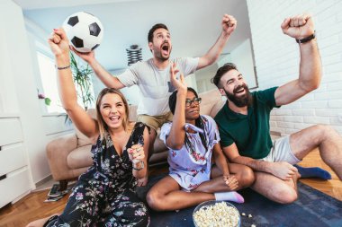 Mutlu arkadaşlar ya da futbol taraftarları televizyonda maç izleyip zaferi evde kutluyorlar. Dostluk, spor ve eğlence kavramı..
