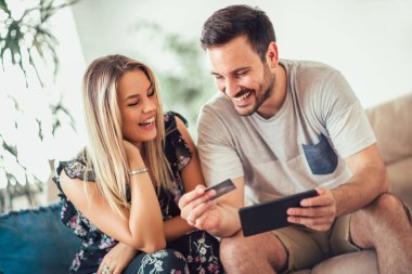 Tablet pc bilgisayar ile çift çift mutlu gülümseyerek ve kredi kartı ev teknolojisi, online alışveriş ve insanlar kavramı 