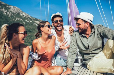 Yelkenli güvertesinde oturup eğlenen arkadaşlar. Tatil, seyahat, deniz, arkadaşlık ve insanlar kavramı.