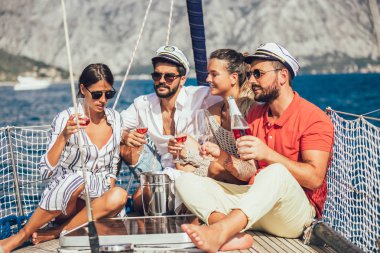 Yelkenli güvertesinde oturup eğlenen arkadaşlar. Tatil, seyahat, deniz, arkadaşlık ve insanlar kavramı.