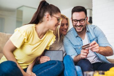 İki kadın ve bir adam alışveriş online kredi kartı ve dijital tablet, oturma odasında