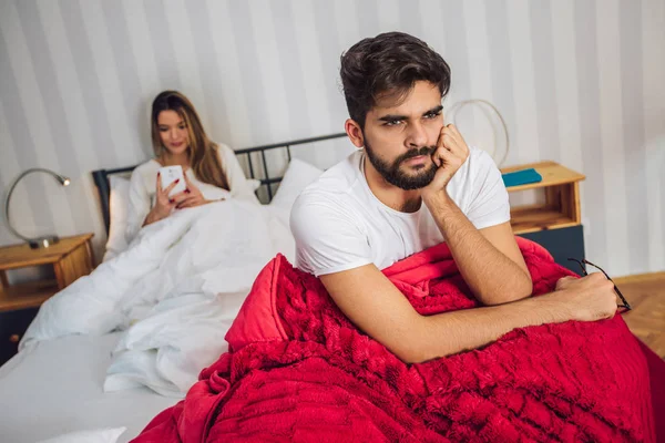 Young upset couple lying separate in a bed, having conflict problem