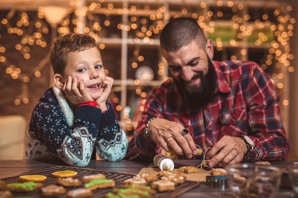 Father and son baking gingerbread Christmas cookies selective focus.