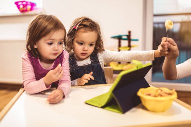 İki sevimli küçük kız bir dijital tablet ile evde oynarken. 