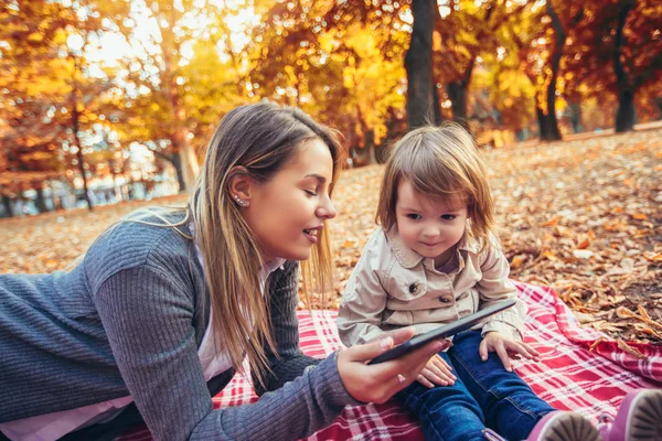 Feliz Madre Sonriente Niño Sienta Juntos Mirando Tableta Parque Otoño —  Fotos de Stock