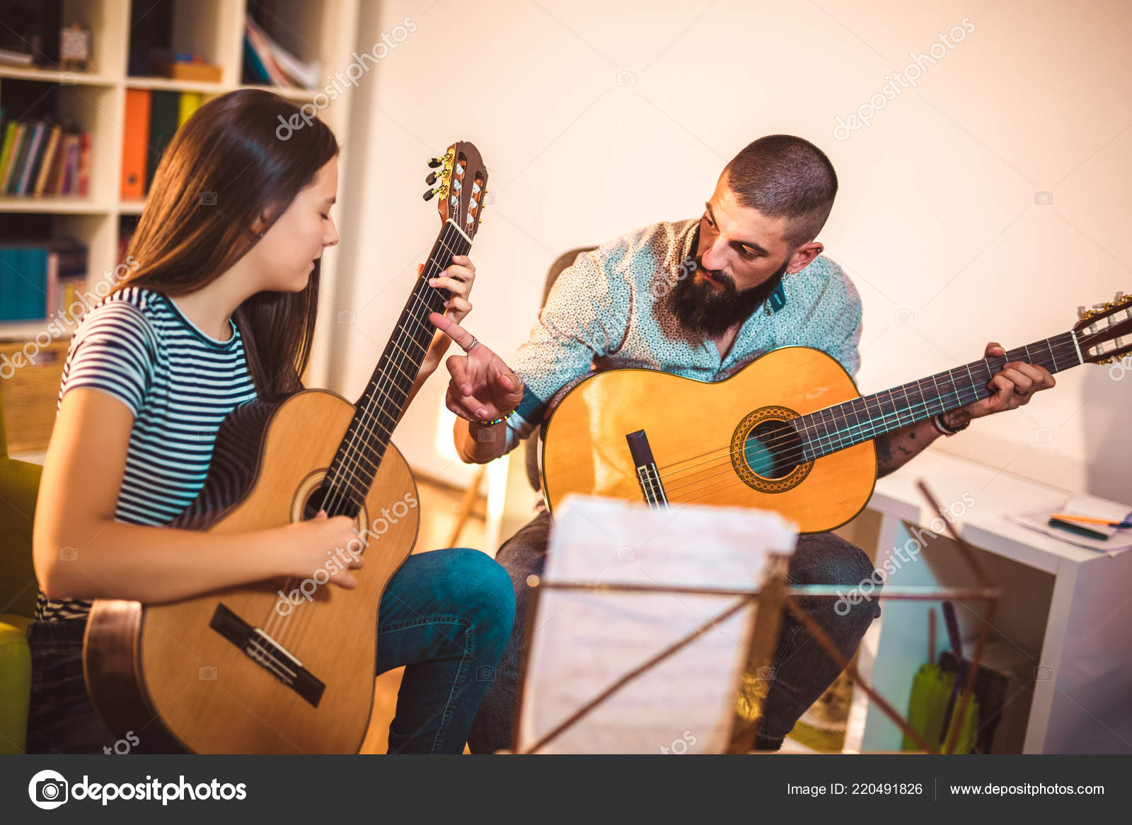 Занятия на гитаре. Бой восьмерка на укулеле. Курсы по игре на гитаре. Мужчина учит играть на гитаре ребенка. Ученик с гитарой.