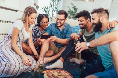 Pizza yemek ve dijital tablet kullanarak genç arkadaş grubu. Ev partisi. Fast food kavramı.