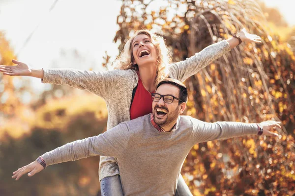 Casal Divertindo Homem Dando Piggyback Para Mulher Parque Outono — Fotografia de Stock