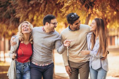 Bir grup genç parkta yürüyor. Arkadaşlar dışarıda eğleniyor.