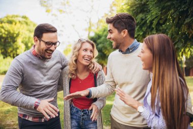 Bir grup genç parkta yürüyor. Arkadaşlar dışarıda eğleniyor.