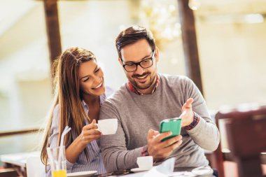 Neşeli delikanlı ve telefonu kullanan kalma ve kafede birlikte vakit kadın.
