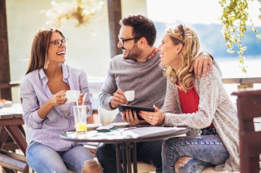 Neşeli grup arkadaşıyla kafede, eğleniyor dijital tablet kullanma.