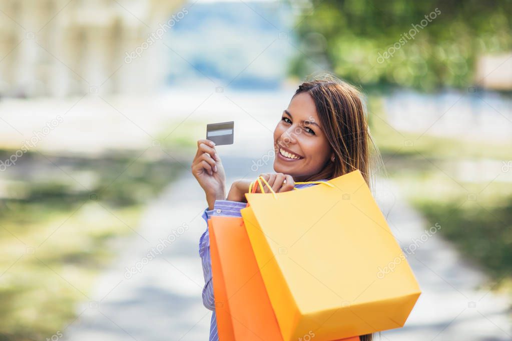 Young beautiful woman holding shopping bags and a credit card