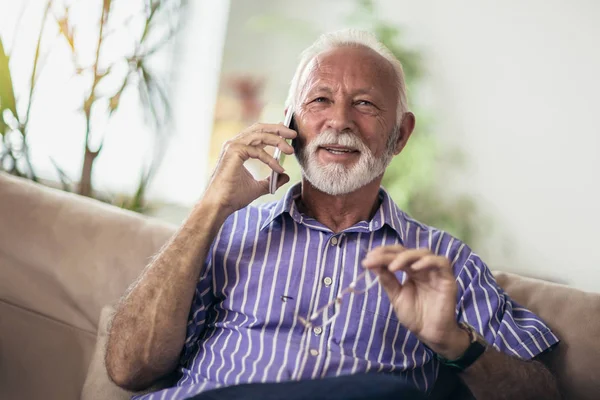 Homem Sênior Conversando Telefone Celular Enquanto Relaxa Sofá Sua Sala — Fotografia de Stock