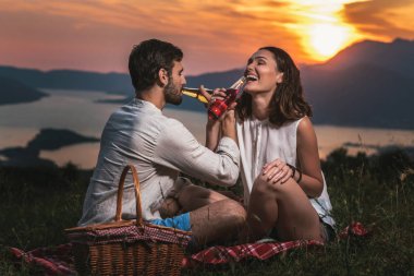 Genç çift arkalarında bir piknik tarihte iyi kez sahip portresi güzel bir gün batımı Boka Bay üzerinde olduğunu.