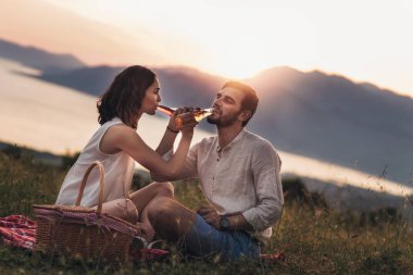 Genç çift arkalarında bir piknik tarihte iyi kez sahip portresi güzel bir gün batımı Boka Bay üzerinde olduğunu.