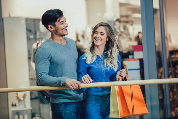 幸せな若いカップルのショッピング バッグを押し — ストック写真