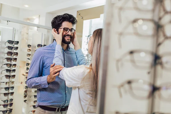 Femaale 眼科光店でメガネを選択する人を支援 — ストック写真