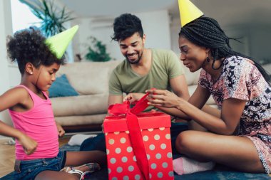 Mutlu siyah aile evde. Afro-Amerikan baba, anne ve Çocuk Doğum günü, kutlama partide eğleniyor. Genç kadın kızına hediye vermek
