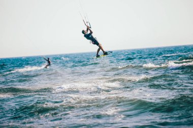 Profesyonel kiter zor hüner güzel bir arka plan üzerinde yapar. Kitesurfing Kiteboarding eylem fotoğraflar adam dalgalar arasında hızlı bir şekilde gider
