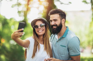 Genç çift cep telefonuyla parkta bir selfie alarak