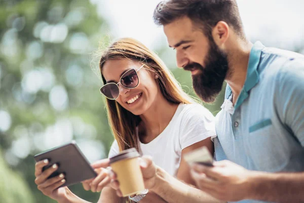 Fröhliches Junges Paar Sitzt Auf Einer Parkbank Und Nutzt Ein — Stockfoto