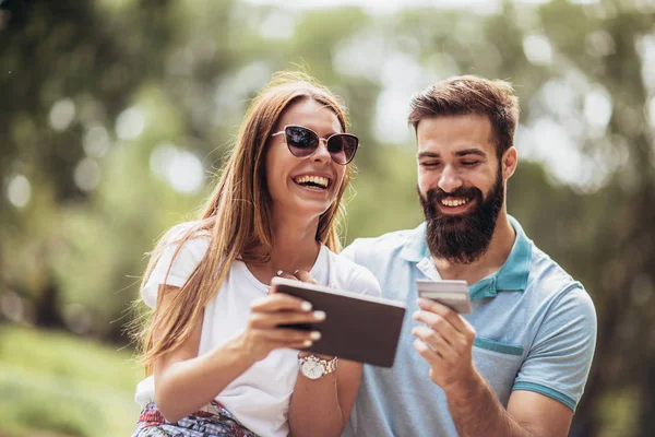 Alegre Joven Pareja Sentada Banco Del Parque Utiliza Una Tableta — Foto de Stock