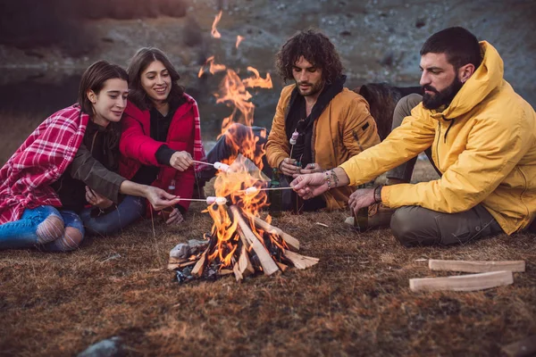 Group of young people around camp fire.