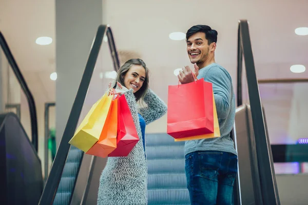 幸せな若いカップルのショッピング バッグを押し — ストック写真