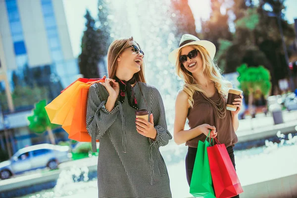 Happy friends shopping. Young friends enjoying shopping in the city, holding shopping bags and coffee to g