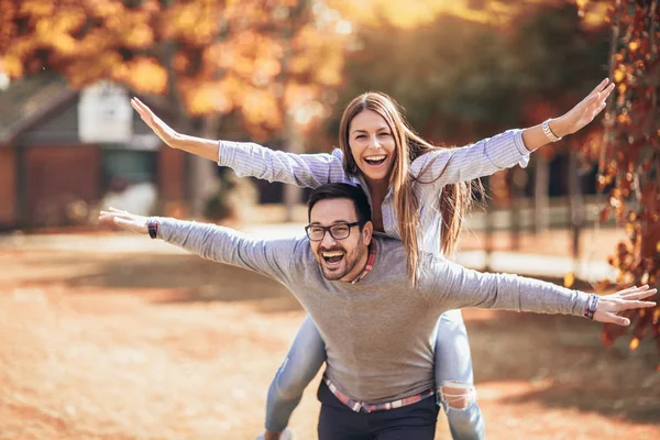 夫妇有乐趣男子在秋季公园背驮女人 — 图库照片