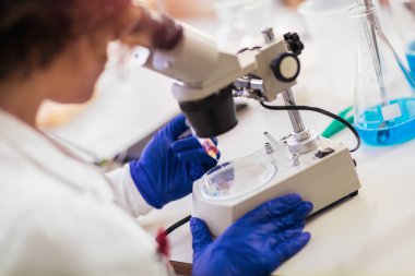 Kadın scienist laboratuvarında. Genç bilim adamı bir laboratuvar mikroskop aramak. Biraz araştırma yaparak genç bilim adamı.