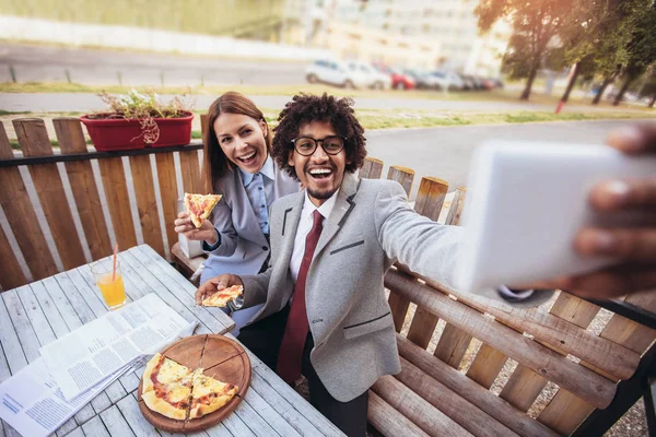 Happy young business team eating pizza in outdoor cafe. Business, food and people concept.