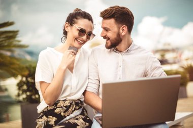 Arka plan üzerinde tekne ile turistik deniz tatil liman tarafından laptop ve kredi kartı kullanarak güzel romantik çift