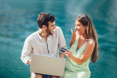 Arka plan üzerinde tekne ile turistik deniz tatil liman tarafından laptop ve kredi kartı kullanarak güzel romantik çift
