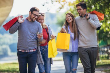Birlikte alışveriş, alışveriş torbaları ve kredi kartı tutan eğleniyor arkadaşlar.