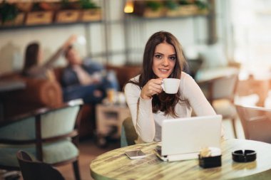 Cafe bar açık dizüstü bilgisayar önünde oturan genç kadın